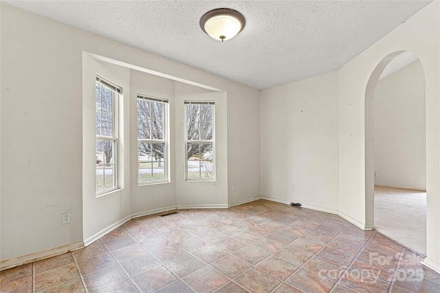 empty room with a textured ceiling and a wealth of natural light