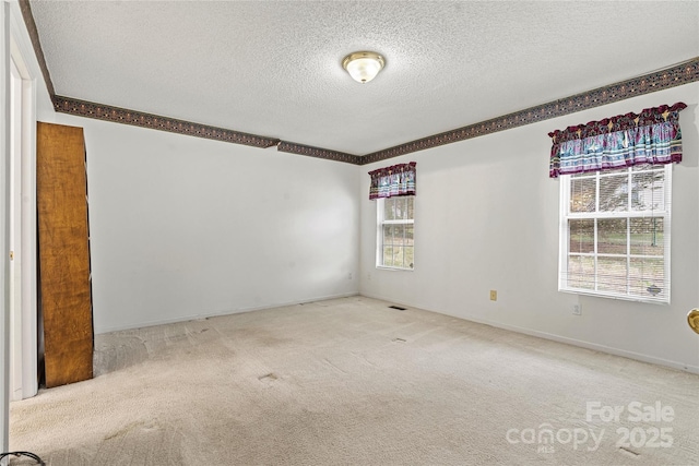 carpeted empty room featuring a textured ceiling