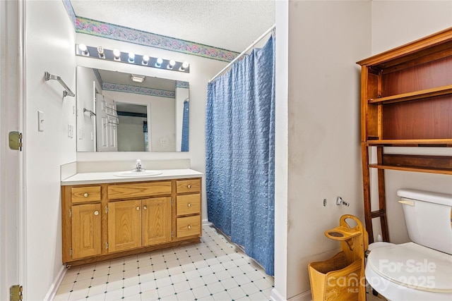 bathroom with vanity, toilet, curtained shower, and a textured ceiling