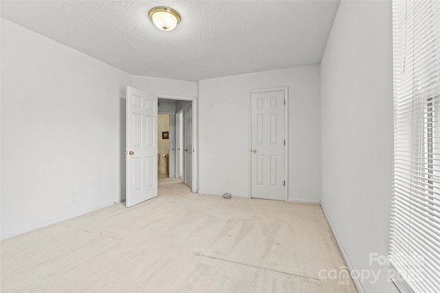 unfurnished bedroom with a textured ceiling, a closet, and light carpet