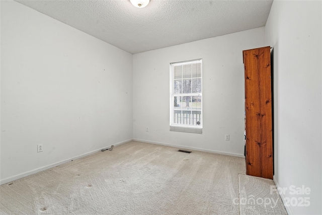 empty room with a textured ceiling and light carpet