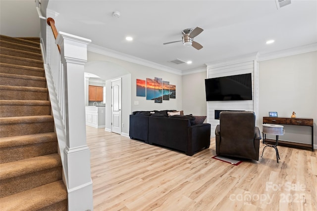 living room with crown molding, light hardwood / wood-style floors, a fireplace, and ceiling fan