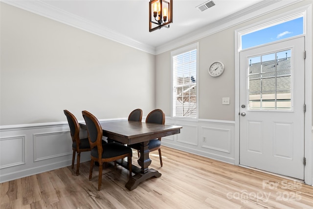 dining room with an inviting chandelier, light hardwood / wood-style flooring, and ornamental molding