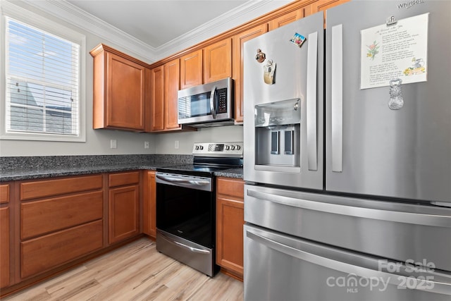 kitchen featuring crown molding, light hardwood / wood-style floors, dark stone counters, and stainless steel appliances