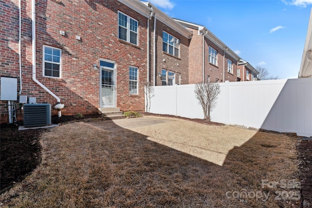 rear view of house featuring cooling unit and a yard