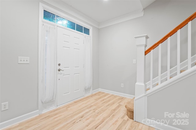 foyer entrance with wood finished floors, stairway, crown molding, and baseboards