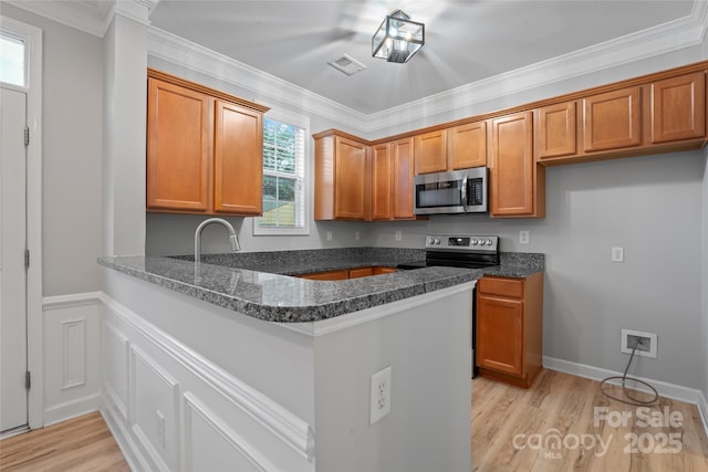 kitchen with appliances with stainless steel finishes, brown cabinets, a peninsula, and crown molding