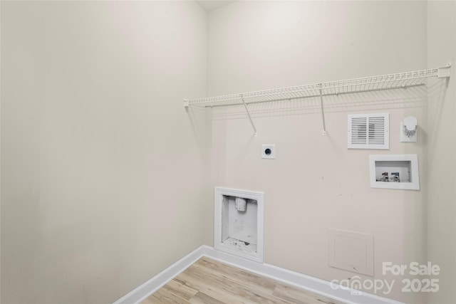clothes washing area with hookup for a washing machine, electric dryer hookup, light wood-style flooring, and baseboards