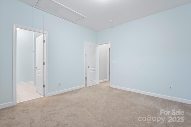 unfurnished bedroom with attic access, carpet flooring, baseboards, and a walk in closet