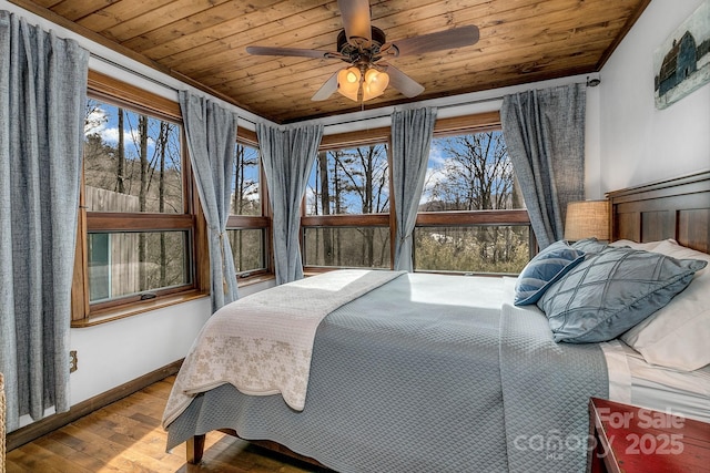 bedroom featuring multiple windows, wood-type flooring, wooden ceiling, and ceiling fan