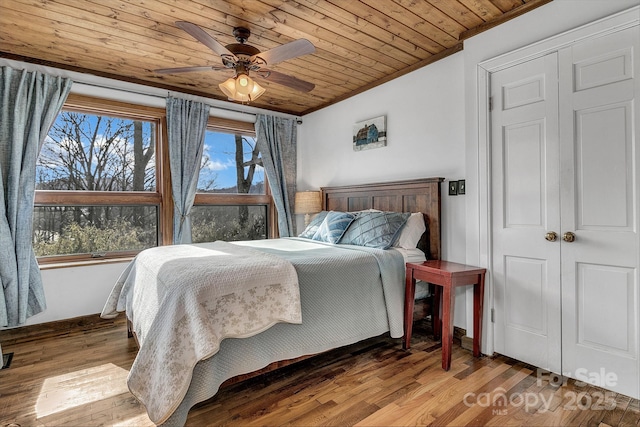 bedroom with crown molding, wood-type flooring, wooden ceiling, a closet, and ceiling fan