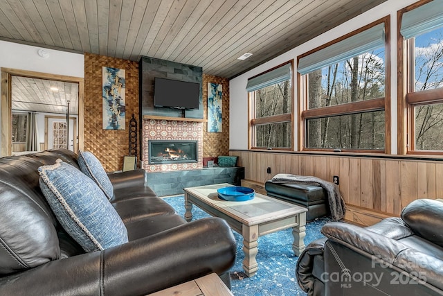 living room featuring wooden ceiling, a fireplace, and wood walls