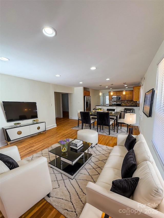 living room featuring light wood-style flooring, baseboards, and recessed lighting