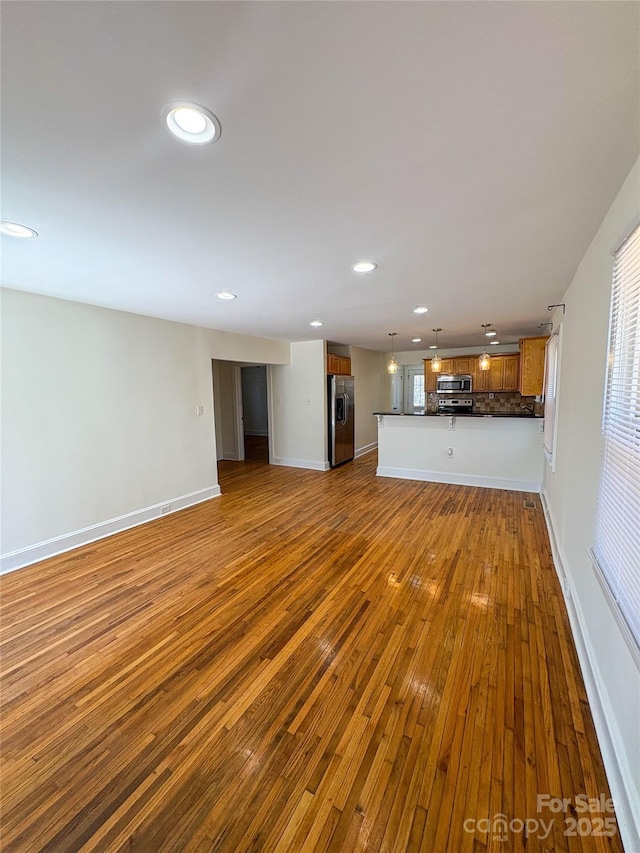 unfurnished living room featuring recessed lighting, dark wood-style flooring, and baseboards