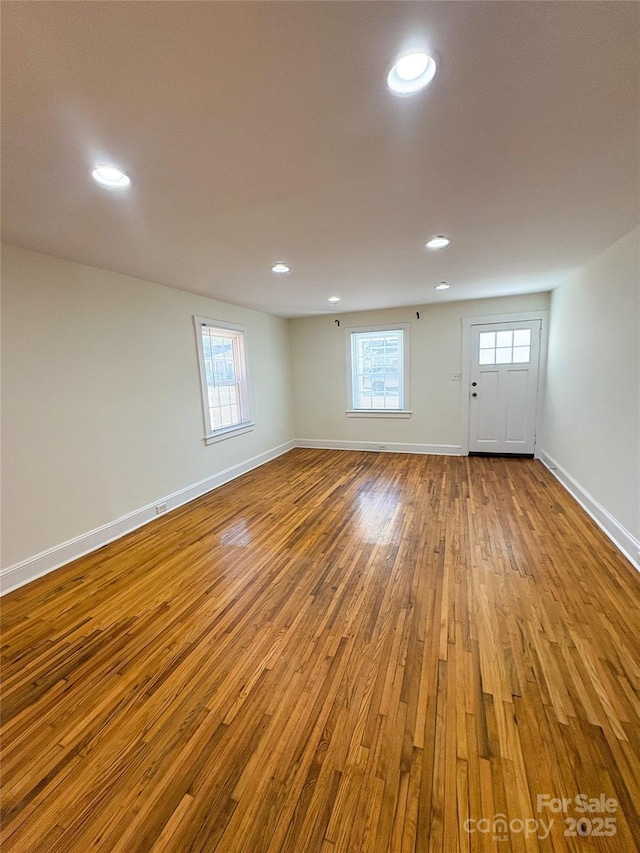 spare room featuring hardwood / wood-style flooring, plenty of natural light, baseboards, and recessed lighting