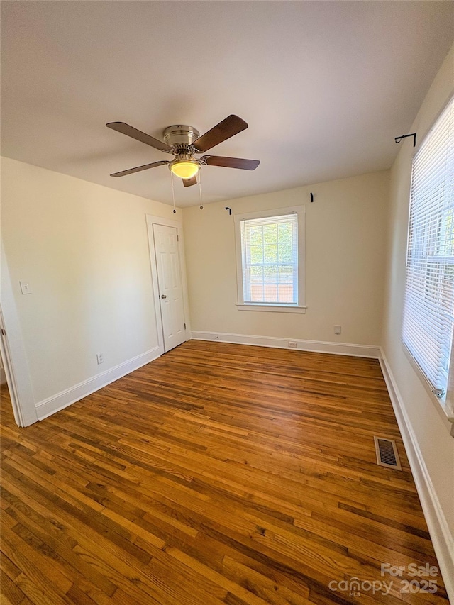 unfurnished room with baseboards, visible vents, ceiling fan, and wood finished floors