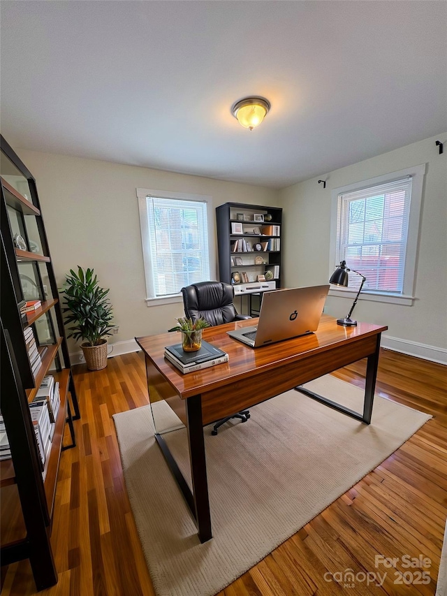 home office featuring a wealth of natural light, baseboards, and wood finished floors