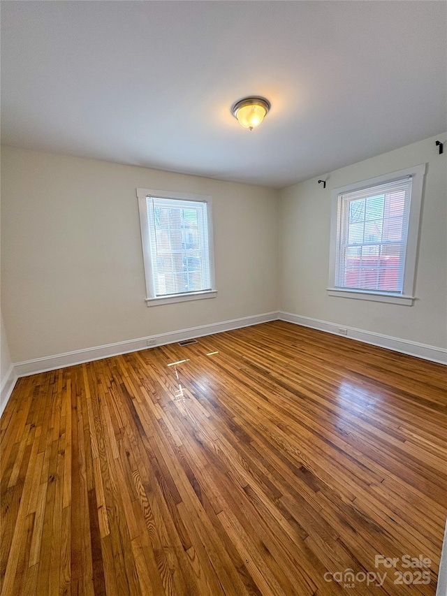 empty room with hardwood / wood-style flooring and a healthy amount of sunlight