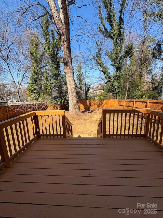 wooden terrace with a fenced backyard