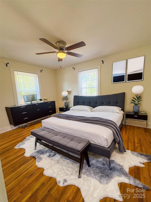 bedroom with ceiling fan, baseboards, and wood finished floors