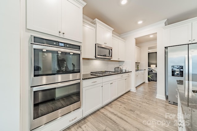 kitchen with white cabinetry, stainless steel appliances, dark stone counters, and tasteful backsplash