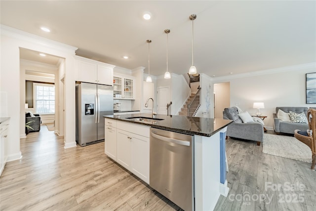 kitchen featuring appliances with stainless steel finishes, sink, decorative light fixtures, white cabinetry, and a center island with sink