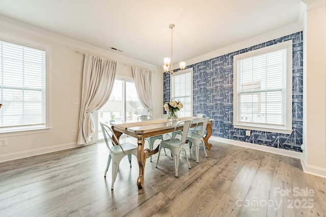 dining area featuring wood-type flooring, crown molding, and a chandelier