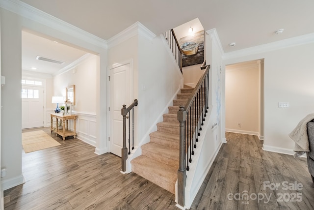 staircase with wood-type flooring and ornamental molding