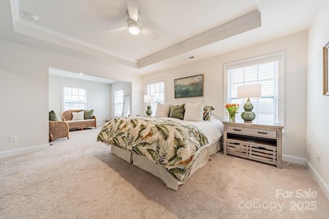 bedroom featuring light carpet, multiple windows, ceiling fan, and a raised ceiling