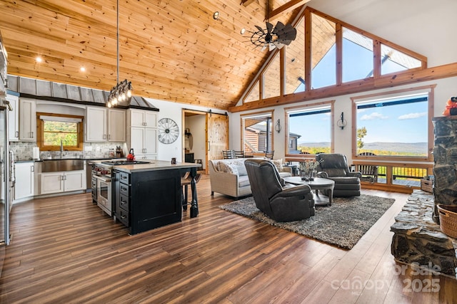 interior space with high vaulted ceiling, decorative light fixtures, backsplash, high end stainless steel range oven, and a center island