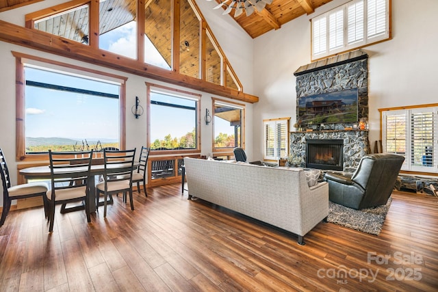 living room with beamed ceiling, wood-type flooring, a fireplace, and high vaulted ceiling