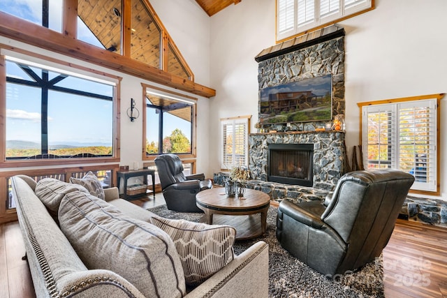 living room featuring hardwood / wood-style flooring, a healthy amount of sunlight, a fireplace, and a high ceiling