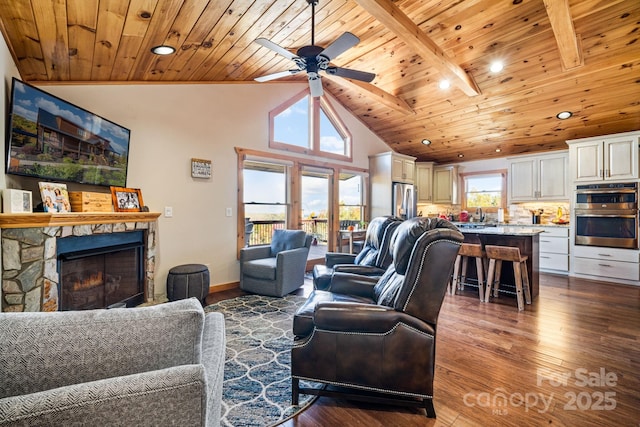 living room featuring wood ceiling, wood-type flooring, a fireplace, and beamed ceiling