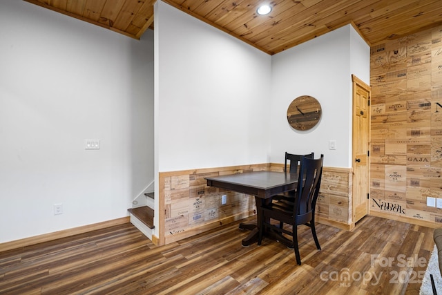 dining space featuring crown molding, dark wood-type flooring, wooden ceiling, and wood walls