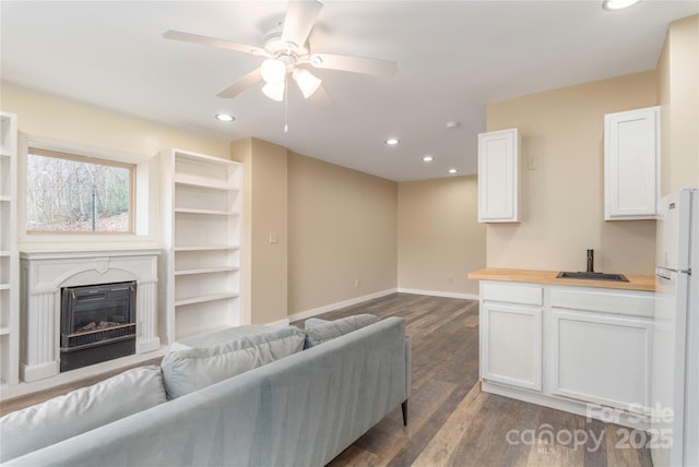 living room with sink, dark wood-type flooring, and ceiling fan