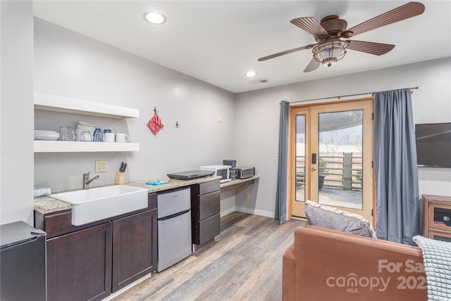 kitchen featuring appliances with stainless steel finishes, sink, ceiling fan, dark brown cabinetry, and light hardwood / wood-style floors