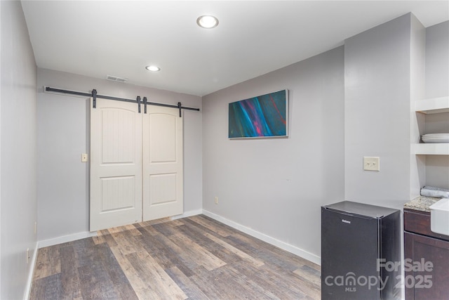 bedroom with a closet, dark wood-type flooring, and a barn door