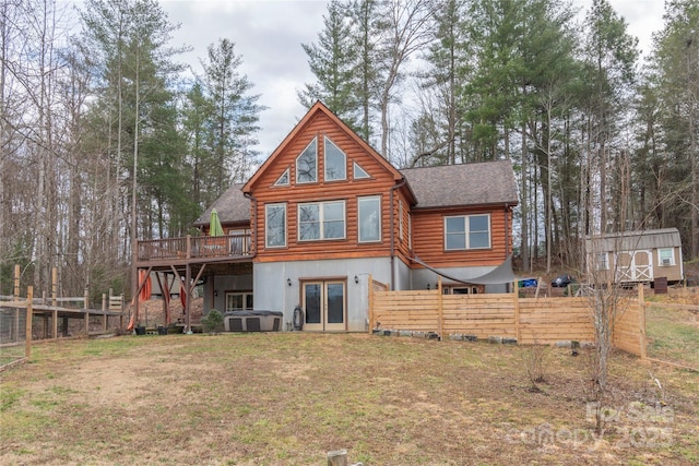 rear view of property featuring a wooden deck, a storage shed, a yard, and french doors