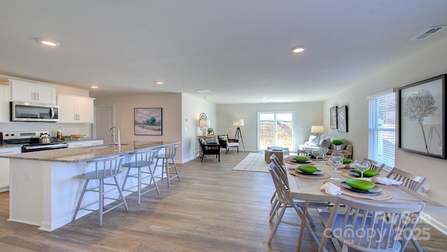 kitchen featuring white cabinetry, a kitchen island with sink, sink, stainless steel appliances, and a breakfast bar area