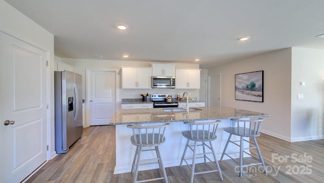 kitchen featuring sink, an island with sink, white cabinetry, and stainless steel appliances