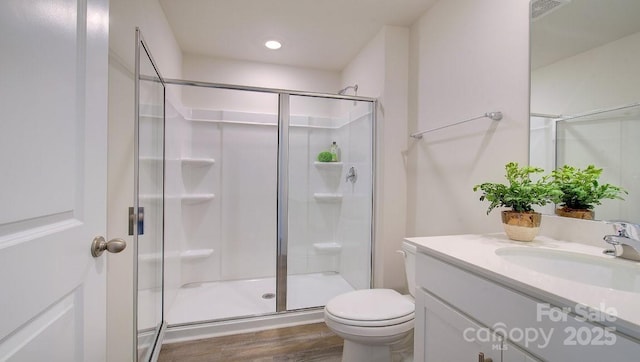 bathroom with wood-type flooring, toilet, a shower with door, and vanity