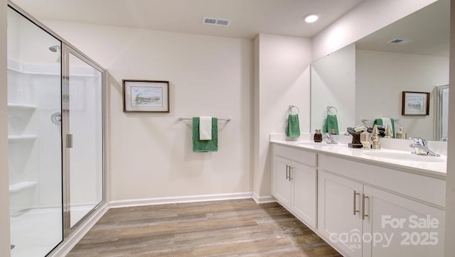 bathroom with wood-type flooring, an enclosed shower, and vanity