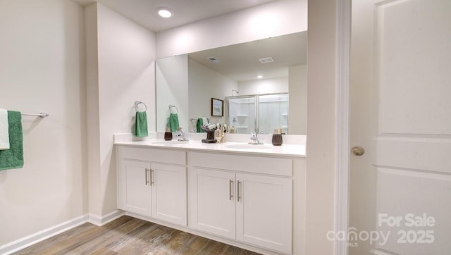 bathroom with wood-type flooring, a shower with shower door, and vanity