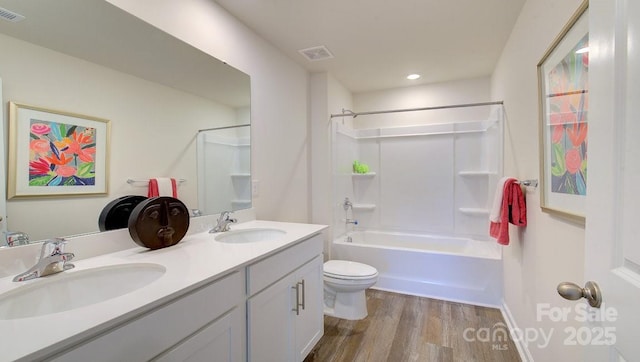 full bathroom featuring hardwood / wood-style floors, toilet, vanity, and  shower combination