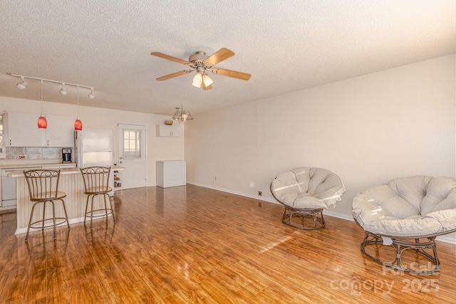 living area featuring ceiling fan, a textured ceiling, and light wood-type flooring