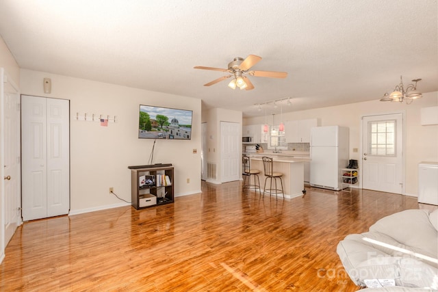 living room featuring ceiling fan, light hardwood / wood-style flooring, and a textured ceiling