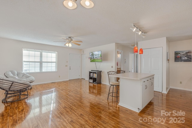 kitchen with white cabinetry, a center island, a textured ceiling, and light hardwood / wood-style flooring