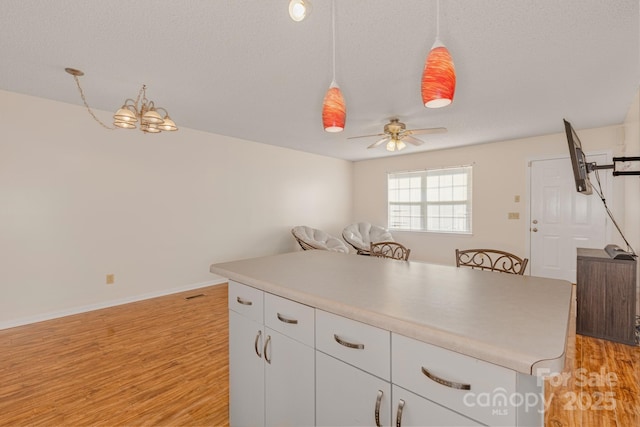 kitchen featuring light hardwood / wood-style flooring, ceiling fan, white cabinetry, hanging light fixtures, and a center island