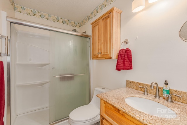 bathroom featuring vanity, a textured ceiling, a shower with shower door, and toilet