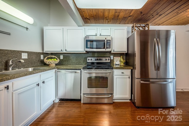 kitchen featuring appliances with stainless steel finishes, sink, dark stone countertops, white cabinets, and backsplash